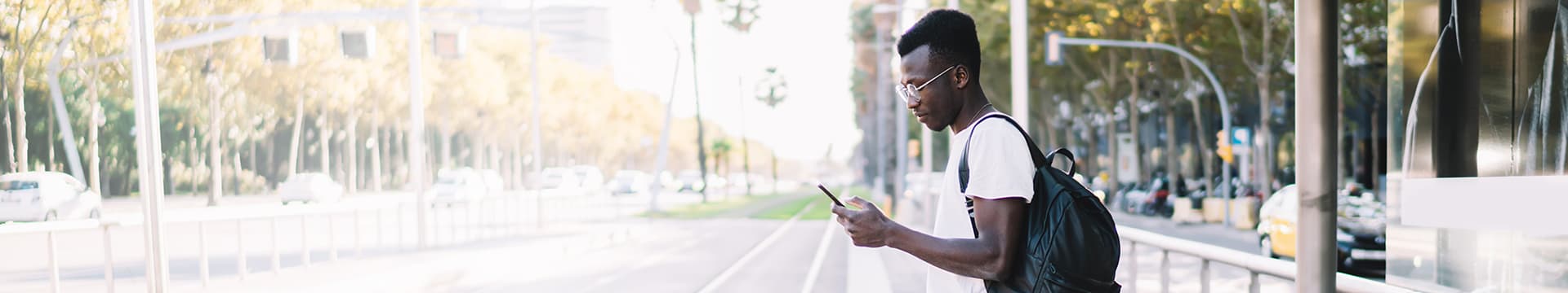 Young man checking phone while waiting for streetcar