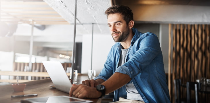 Man smiling at laptop coffee shop