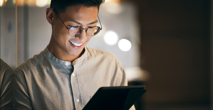 Man with glasses smiling at tablet