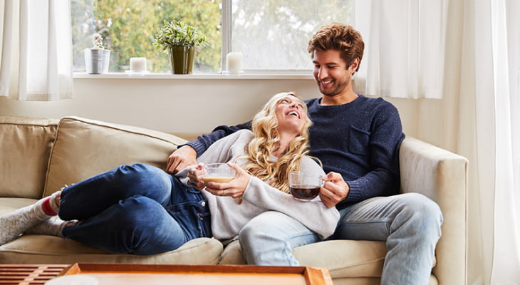 young couple drinking coffee smiling on couch