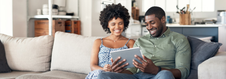Happy couple on couch with tablet