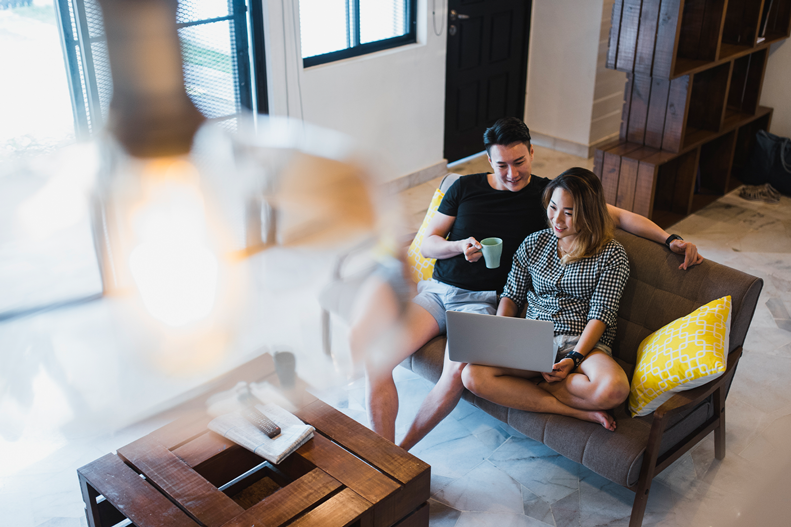 couple sitting on a sofa using their laptop