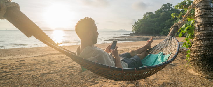 Man relaxing in hammock on phone