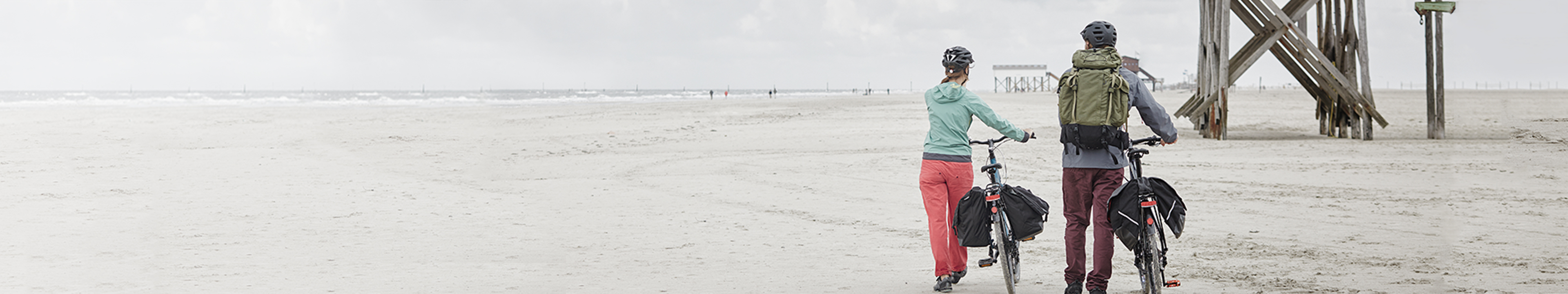 Couple walking with their bikes on a beach