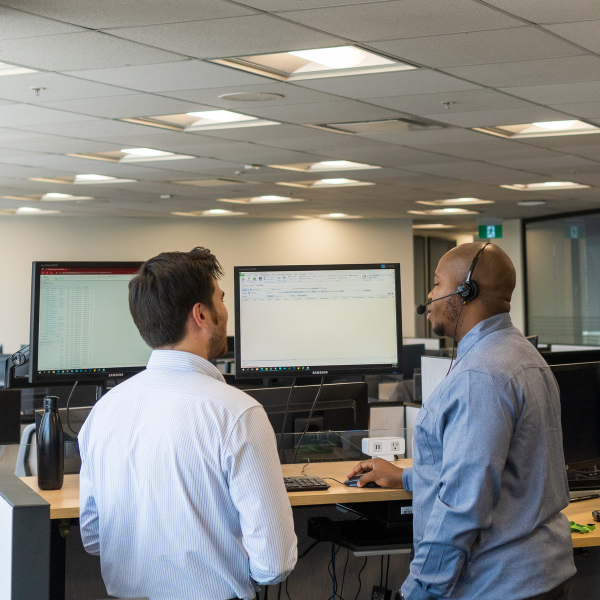 Two employees standing looking at a pc screen