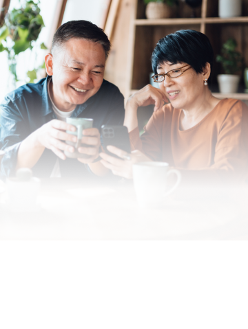 A couple smiling while looking at a smartphone.