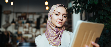 A woman in a headscarf looking at a tablet.