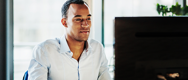 A man sitting at a desk with multiple monitors.